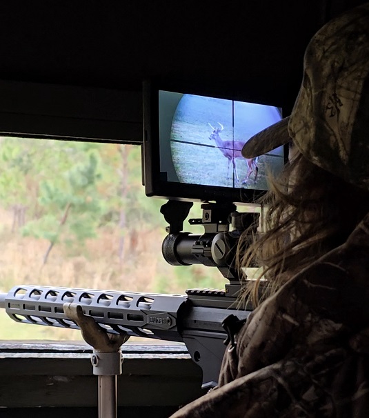 Hunter in deer blind with deer in sight using Digital Crosshairs 1000SA adaptive rifle scope clip-on